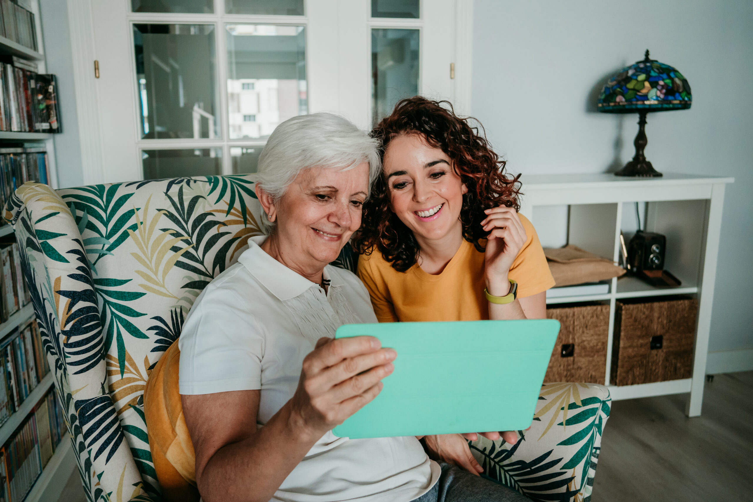 Mother and daughter making a video call through their tablet while isolated at home. Social distancing caused by covid19.